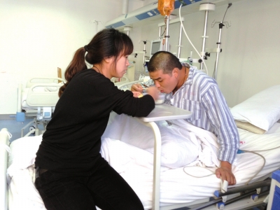昨天，在事故中救出5名工友的宋吕锋在医院接受妻子照顾。京华时报记者陶冉摄/视频
