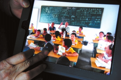 老人展示在希望学校和孩子们互动时的照片。