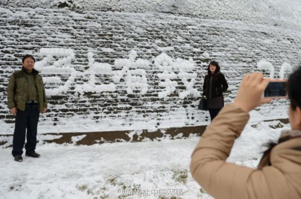 游人在城墙上用积雪拼出“马上有钱”