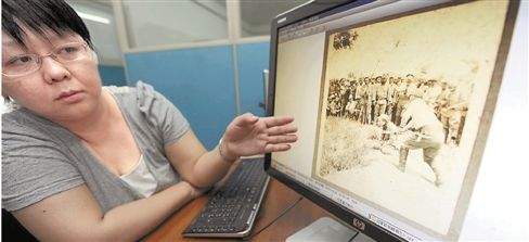 6月12日，中国第二历史档案馆工作人员展示申报档案中由日军拍摄的屠杀照片。 新华社发