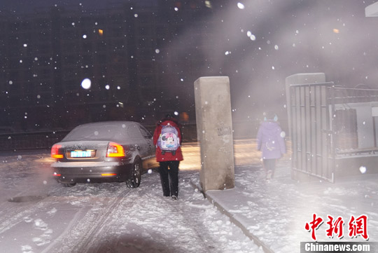12月14日清晨，北京降雪仍在继续，市民雪中出行。中新网记者 周维 摄