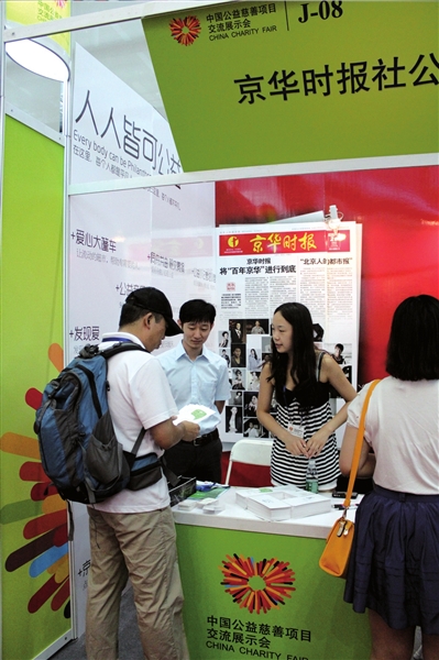 参观者在本报展台了解《公益周刊》的报道理念和公益活动。王鹤鸣供图
