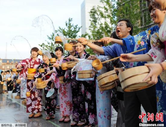 当地时间7月27日，日本东京，上班族身穿夏季休闲和服或浴衣，站在市中心街头洒水。洒水可以直接缓解地表温度，并抑制尘土飞扬。当日东京地区气温飙升至35摄氏度。