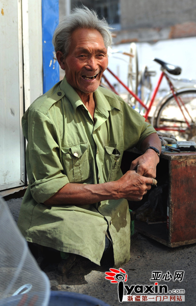 图为8月13日，乌市大湾南路，67岁的夏长流在修理自行车。亚心网记者
