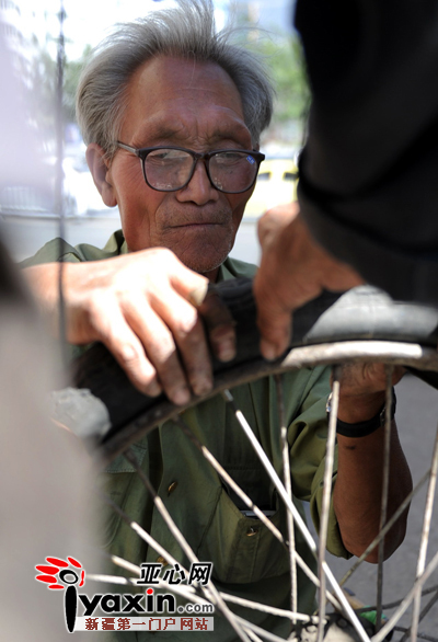 图为8月13日，乌市大湾南路，67岁的夏长流在修理自行车。亚心网记者