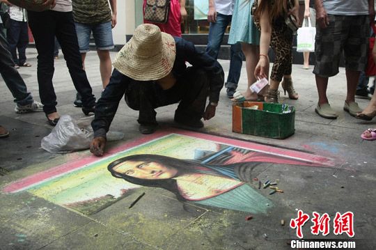 9月9日，一名乞丐在重庆市沙坪坝区步行街上，头戴草帽身穿一袭破旧蓝衣在地上正画《蒙娜丽莎的微笑》。中新社发