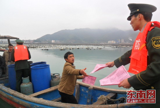 图为边防官兵为渔船民发放海上110接处警知识宣传单