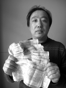 李龙拿着一摞诉状的快递回单。从2008年开始，他先后向法院递交了20余个行政案件的诉状。图/记者周喜丰