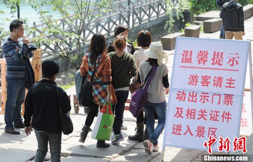 4月14日，几位游客未能“躲过”凤凰古城卡口地盘查，工作人员请其出示门票。中新社发 一默 摄