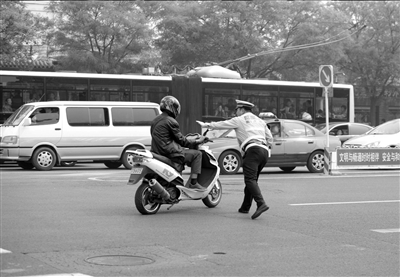 地安门路口，一辆摩托车违章行驶，不顾交警阻拦，加大油门欲逃避处罚。