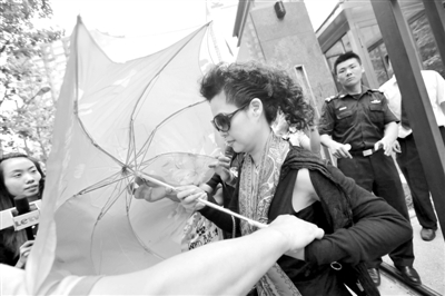 走出法庭的梦鸽用雨伞遮挡记者拍照。昨天，李某涉嫌强奸一案在法院召开庭前会议，梦鸽作为李某的法定代理人身份参加了会议。