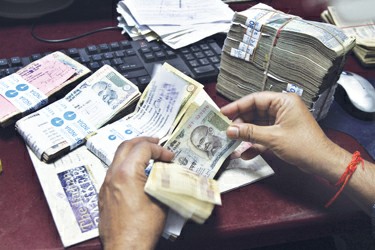 图片说明:印度货币兑换中心工作人员在清点卢比 图IC